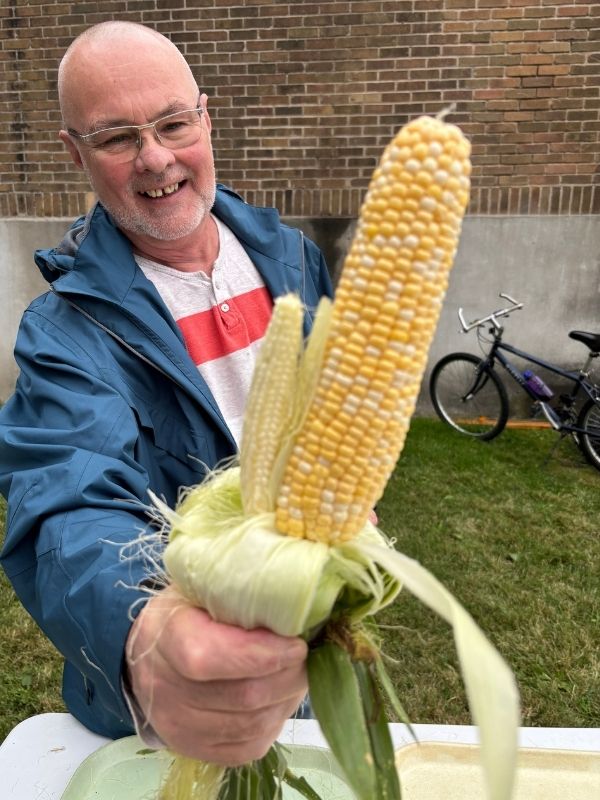 Participant avec des épis de blé d’Inde lors de l’épluchette des Porteurs d’Espérance à Longueuil